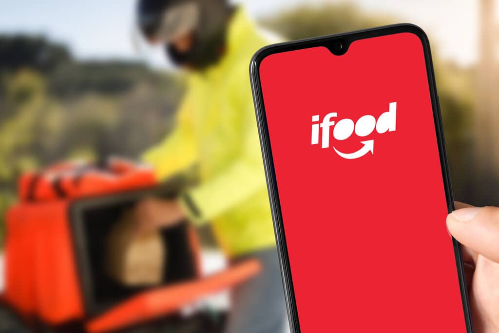 celular com o aplicativo do ifood aberto e motoboy atras