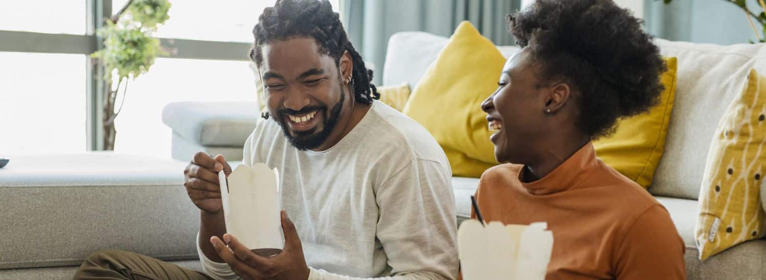 dia do consumidor: casal se divertindo enquanto come em casa