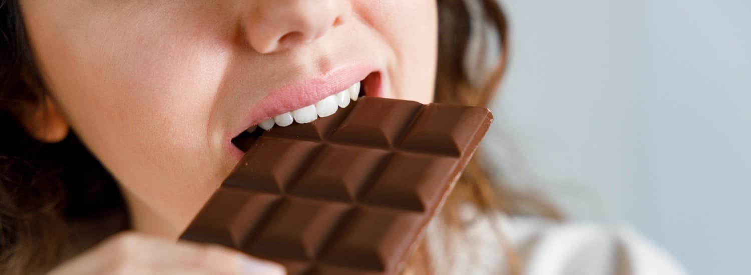dia do chocolate: mulher mordendo barra de chocolate