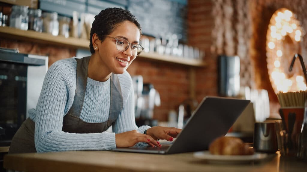 mulher feliz olhando notebook em restaurante