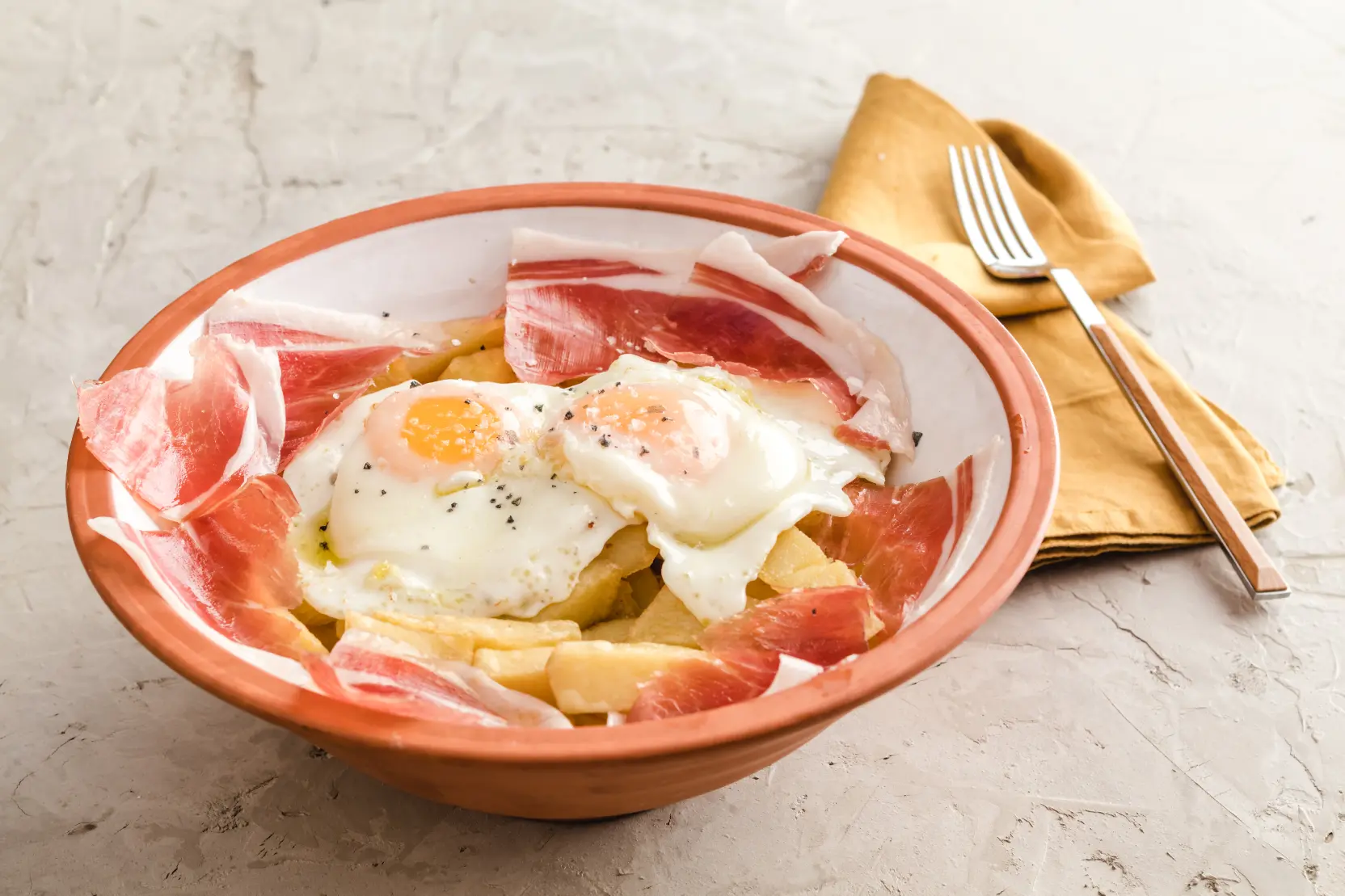 Huevos rotos, prato típico da culinária espanhola com ovos fritos, batata frita e presunto cru