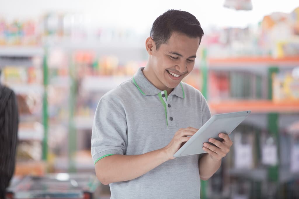 homem sorrindo e olhando para um tablet