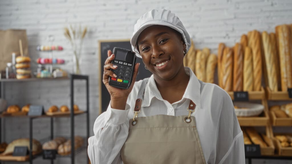 mulher sorrindo com uma maquina de cartao de credito na mao