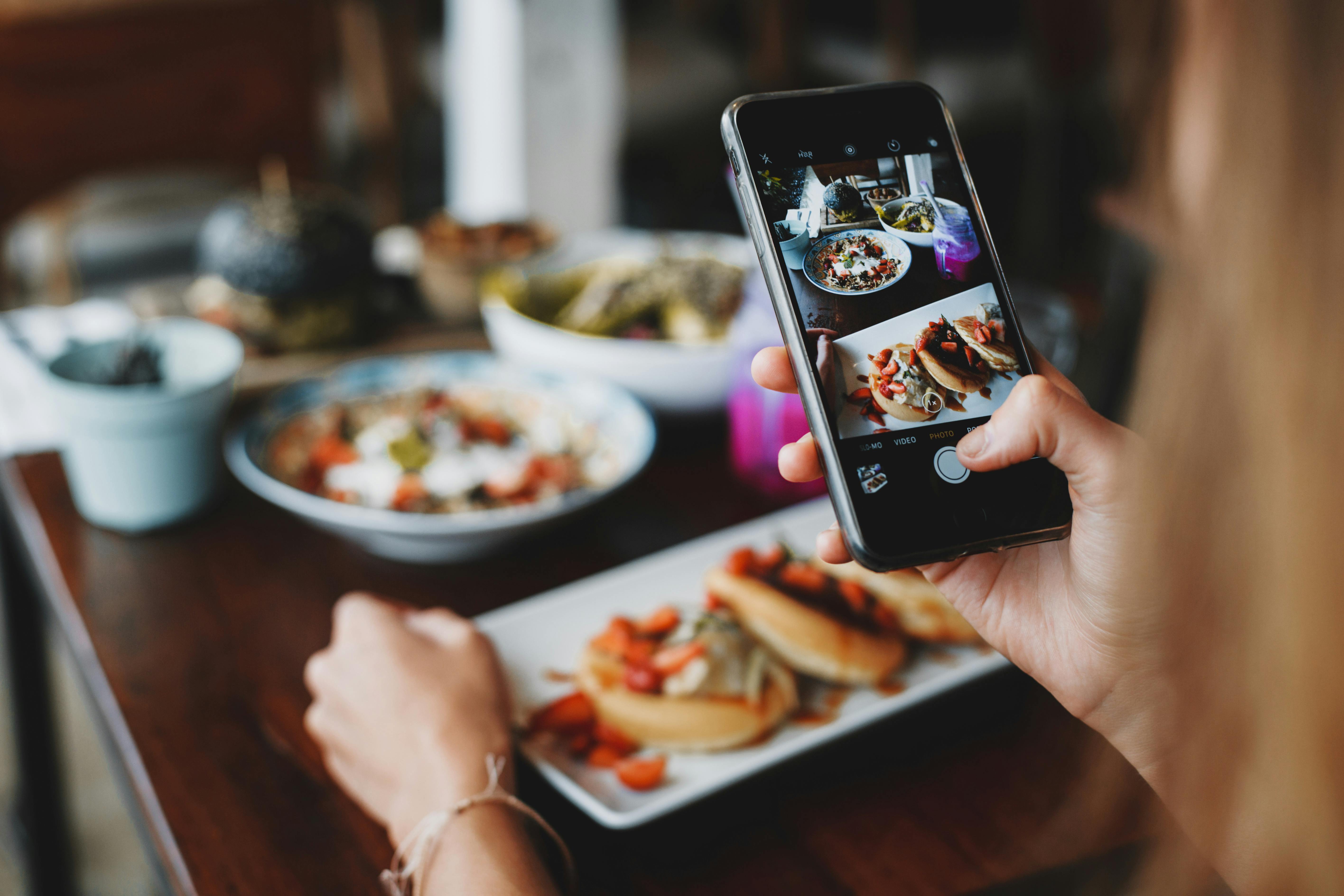 foto de uma pessoa com o celular, mostrando como tirar fotos de comida no ifood