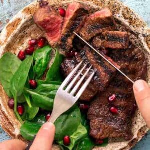 acompanhamento para churrasco: prato de churrasco com salada com garfo e faca de pessoa por cima