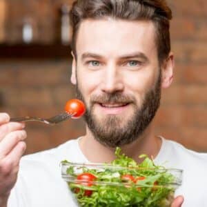 alimentação saudável: pessoa sorrindo e comendo um prato de salada