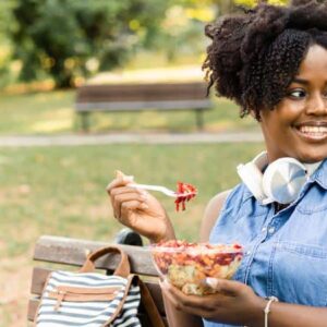 cardápio sem glúten: pessoa sorridente ao comer em um parque