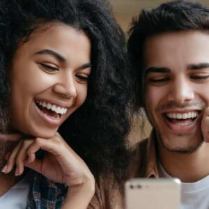 cashback: casal de homem branco e mulher negra sorrindo enquanto olham para um celular