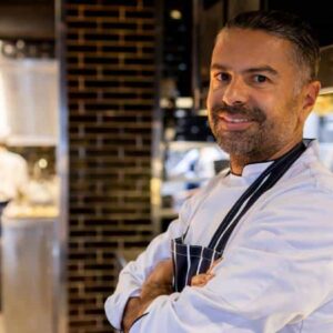 cerâmica para cozinha: cozinheiro de uniforme e avental sorrindo dentro da cozinha