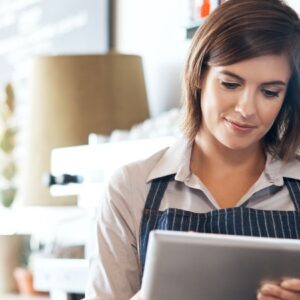 certidão negativa federal: mulher empreendedora de avental e atrás do balcão de bar com um tablet na mão.