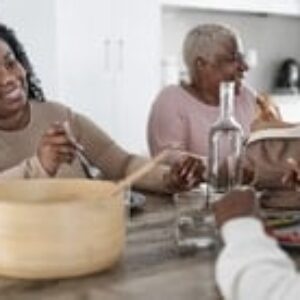 Happy afro Latin family eating healthy lunch with fresh vegetabl