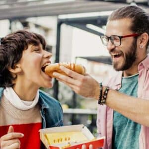 como abrir um carrinho de cachorro quente: pai e filho comendo cachorro quente e sorrindo