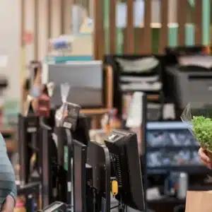 Mulher e criança compram uma alface em um mercadinho e o vendedor entrega o produto a elas