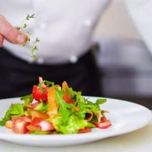 decoração de saladas: chef de cozinha terminando de preparar prato de salada