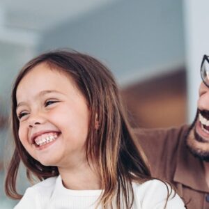 dia dos pais: pai segurando filha pequena sorrindo e felizes