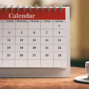calendário sobre uma mesa de madeira com uma xícara de café ao lado