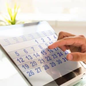 feriados em setembro: mão de homem sentado em mesa conferindo um calendário