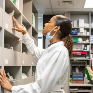 Farmacêutica olha os medicamentos na prateleira