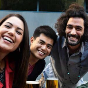 happy hour: grupo de amigos diversos em bar com drinks tirando uma selfie