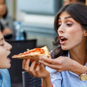 lactose: mãe dando pedaço de pizza na boca da filha