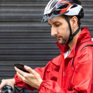 logística 4.0: entregador de comida parado com a bicicleta olhando para celular.