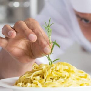 nichos de mercado em alta: cozinheiro terminando de fazer um prato para ser servido.