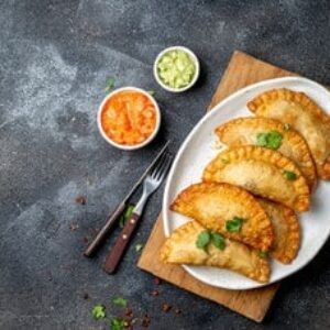 Latin American fried empanadas with tomato and avocado sauces. Top view
