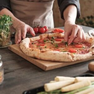 Decorating hot pizza with herbs