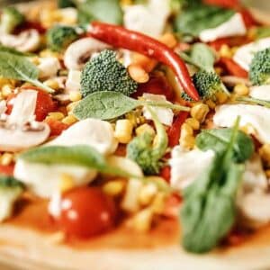 pizza vegana: imagem de mãos de pessoa branca segurando uma pizza coberta de vegetais