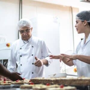 produtividade: confeiteiros diversos preparando porções de doces com confeiteiro chefe auxiliando as auxiliares.