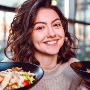 reducitarianismo: pessoa sorrindo e segurando dois pratos de saladas e vegetais