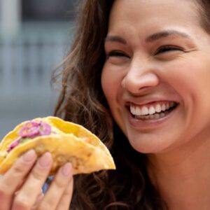 restaurante mexicano: mulher sorrindo segurando um taco na mão