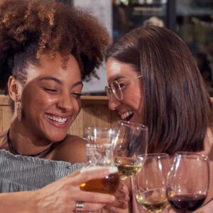 restaurantes em curitiba: quatro amigas de etnias diferentes em restaurante brindando com taças de vinho.