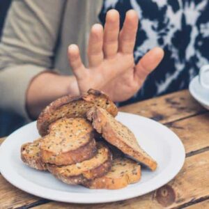 restrição alimentar: pessoa indicando com a mão que não quer um prato de fatias de pão