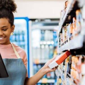 rfid: pessoa colaboradora de estabelecimento pegando item na prateleira e checando tablet