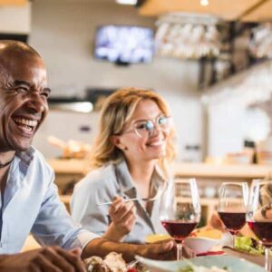 taxa de desperdício: grupo de amigos diversos se divertindo enquanto comem em restaurante