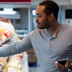 tipos de queijo: homem negro dentro de supermercado escolhendo queijos