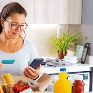 vale-alimentação: mulher fazendo pagamento de compras dentro de casa com cartão